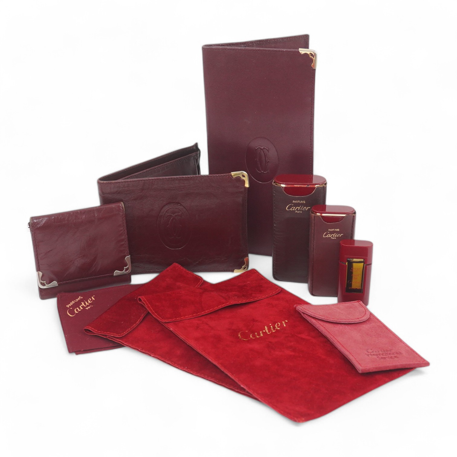 An assortment of Must de Cartier bordeaux leather accessories